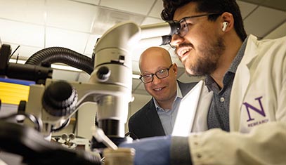 Jonathan Rivnay observing one of his research group members as he inspects a biohybrid device.